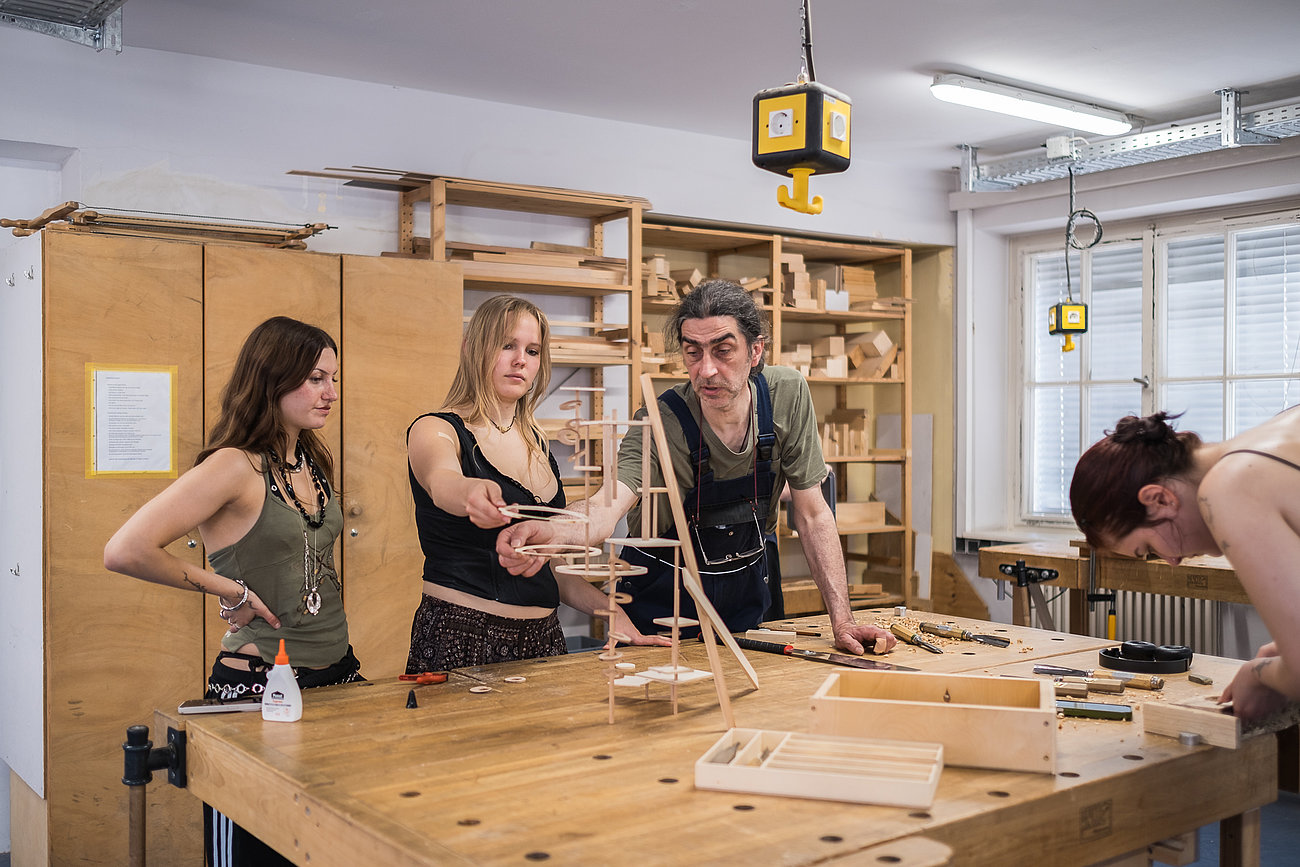 Eine Gruppe bespricht Werkstücke in der Holzwerkstatt