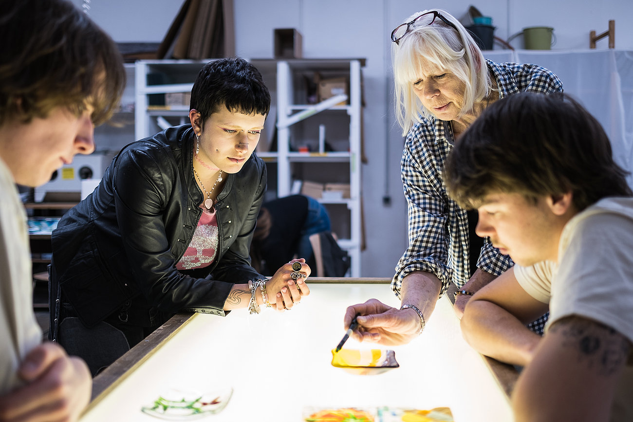 Eine Gruppe bespricht Werkstücke in der Glaswerkstatt.